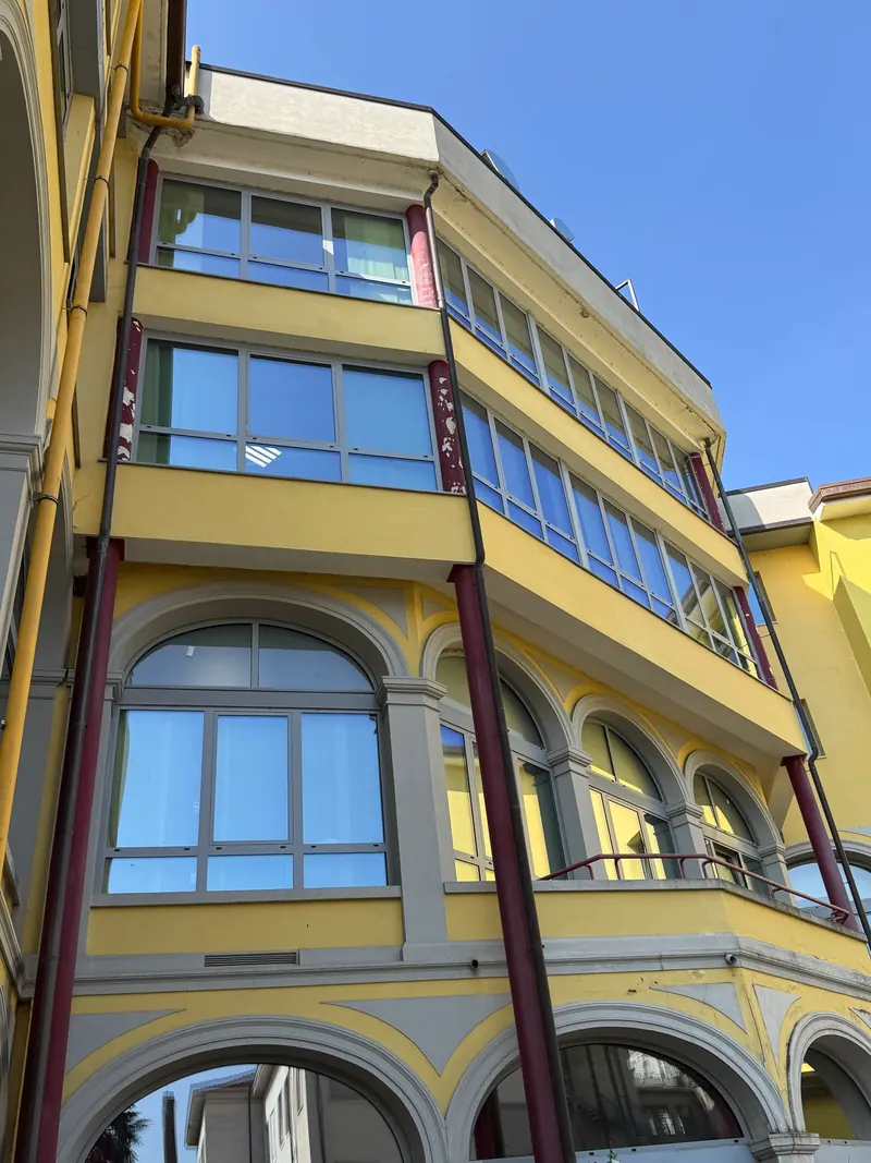 Yellow building with arched windows and large glazing on every floor