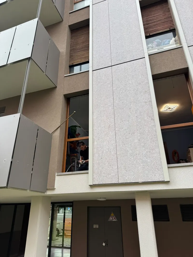 Façade of an apartment block with balconies and grey panels