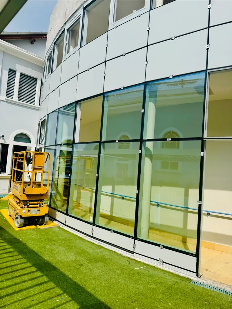 Facciata vetrata curva di un edificio durante i lavori, con piattaforma elevatrice