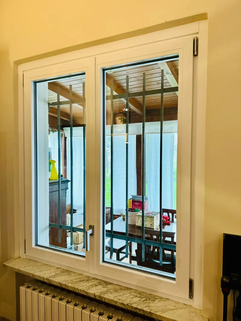 White two-leaf window with an outside security grille