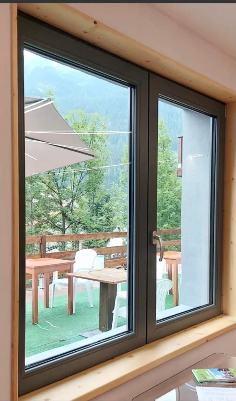 Two-leaf window with a brown frame overlooking a terrace