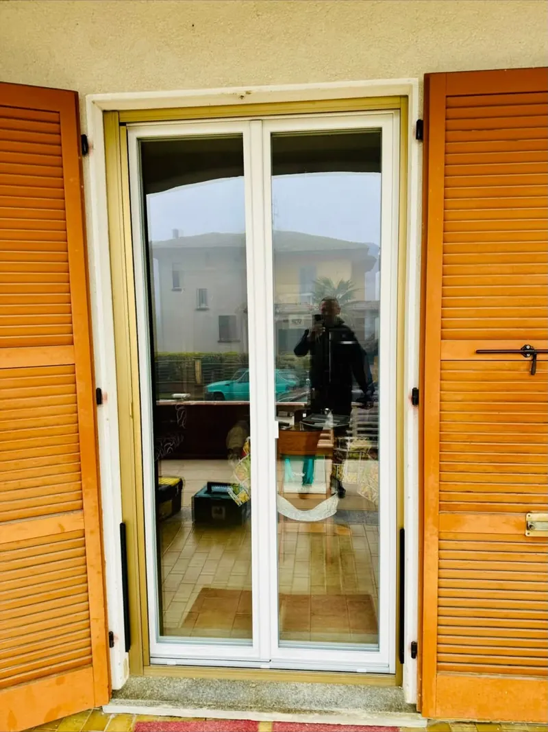 Porta finestra bianca con persiane in legno aperte ai lati