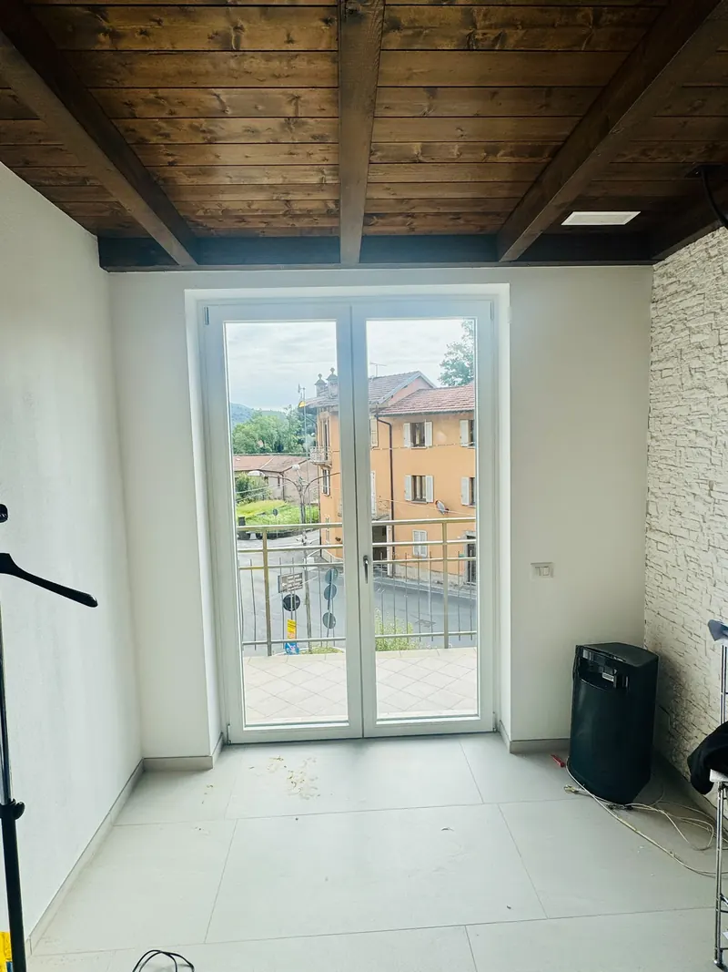 Porta finestra bianca a due ante in una stanza con soffitto a travi di legno