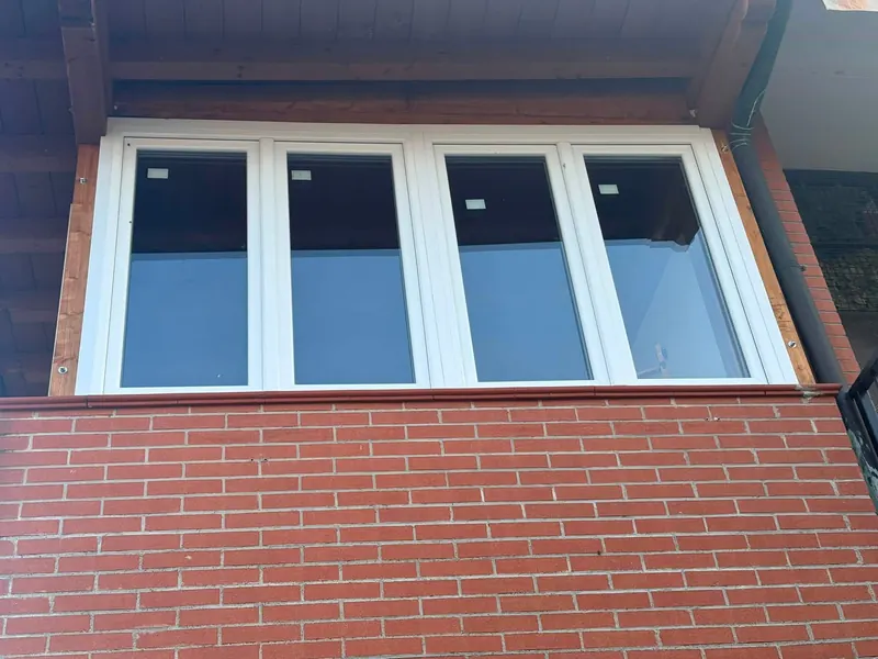 Serramento bianco a quattro ante sopra un muro in mattoni, visto dall'esterno